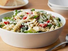 a white bowl filled with pasta salad on top of a wooden table