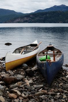 two canoes sitting on the shore of a lake