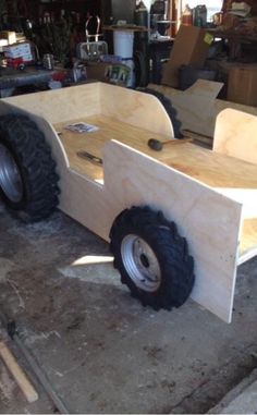 a wooden trailer with wheels on the floor in a workshop area, ready to be built