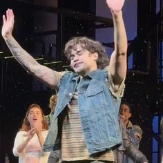 a man with his arms in the air and two women standing on stage behind him