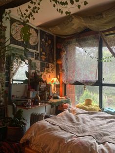 a bed sitting under a window next to a lamp and potted plant in a room