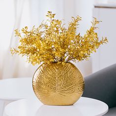 a vase with some yellow flowers in it on a white table next to a chair