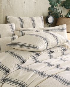 a bed with white and black striped comforter next to a potted green plant