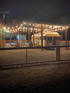 an rv is parked in front of a fence with lights on it at night time