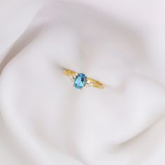 a close up view of a ring with a blue stone in the middle on a white cloth