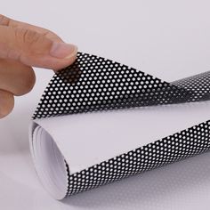 a hand is pointing at a black and white dotted piece of paper that has been folded