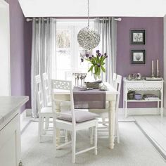 a dining room with purple walls and white furniture