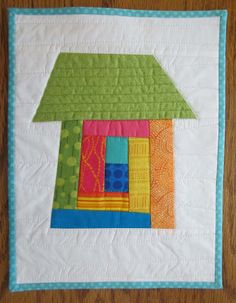 a quilted wall hanging with a house on it