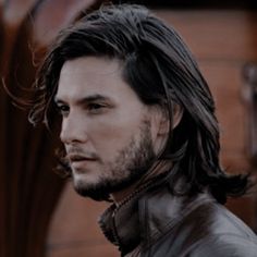 a man with long hair wearing a leather jacket and standing in front of a building