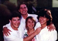 a group of young men standing next to each other smiling for the camera with their arms around one another