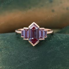 a pink tourmaline stone ring sitting on top of a green surface