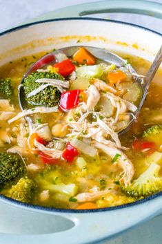 a bowl of soup with broccoli, carrots, and chicken in it