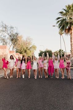 a group of women standing on the side of a road with their arms in the air