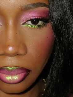 a close up of a woman with pink and green eyeliners on her face