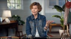 an older woman sitting in a chair with her hands out to the side while talking