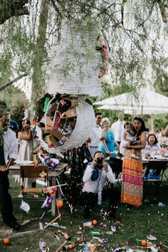 a group of people sitting under a tree with confetti falling from the branches