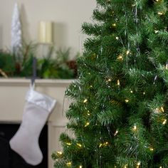 a small christmas tree with white lights next to a fireplace