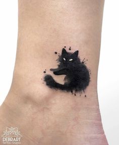 a black cat tattoo on the ankle with watercolor paint splatters all over it