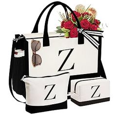 a white and black tote bag with flowers in it next to two matching purses