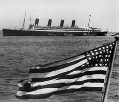 an american flag flying in front of a large ship