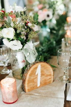 the table is set with candles and flowers in vases on top of wood slices