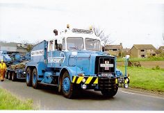 a large blue tow truck driving down a road