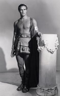 a man in roman garb standing next to a column