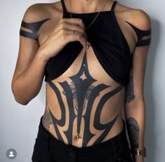 a woman with tattoos on her chest and arm is holding something in her right hand