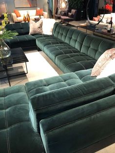 a living room filled with lots of green couches and furniture in front of a mirror