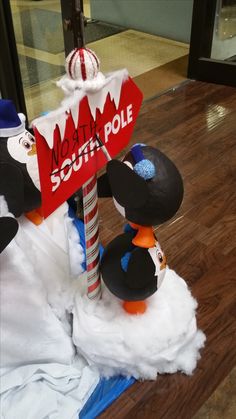 a couple of snowmen standing next to a red sign that says north south pole