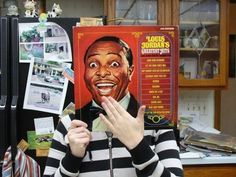 a woman holding up a magazine with an image of louis jordan on it's face