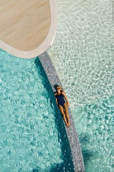 a woman in a blue swimsuit is floating on the edge of a swimming pool