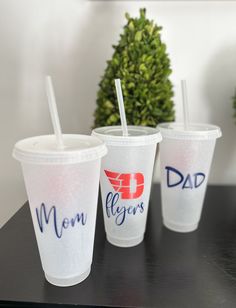 three disposable cups with straws on top of a table