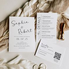 the wedding stationery is laid out next to each other on top of some feathers