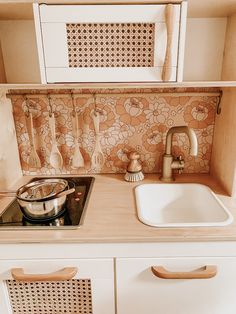 a white kitchen sink sitting under a window next to a stove top oven and cupboards