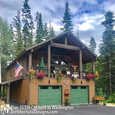 a large wooden building with green garage doors and flowers on the balcony, along with an american flag