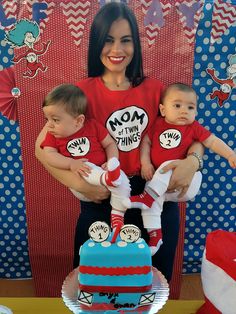 a woman holding two babies in front of a cake with dr seuss on it