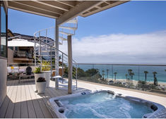 a hot tub sitting on top of a wooden deck next to an ocean front building