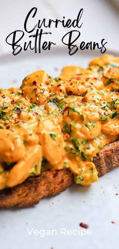 a close up of a sandwich on a plate with the words curryed butter beans