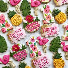 decorated cookies are arranged on a table for a birthday or baby shower party with flowers, pineapples and flamingos