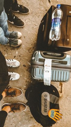 several people standing around with their luggage and water bottles on the ground in front of them