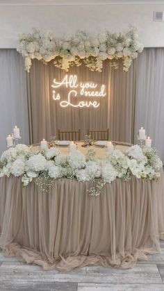 an all you need is love sign on the wall above a table with flowers and candles