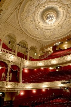 an auditorium with red seats and chandeliers on the ceiling is seen in this image