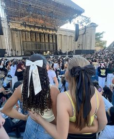 two women sitting in front of an audience at a music festival with their backs to each other