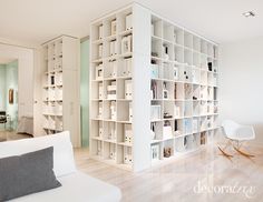 a living room filled with lots of white bookshelves next to a dining room table