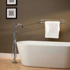 a white bath tub sitting on top of a hard wood floor next to a wall