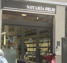 a scooter is parked in front of a building that says notaroia feliu