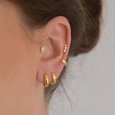 a close up of a person's ear with two small gold earrings on it