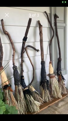 several brooms are lined up on the side of a house, and one is hanging upside down