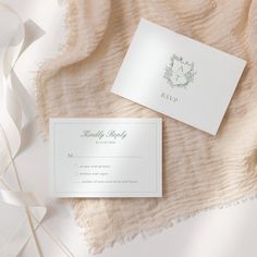 the wedding stationery is laid out on top of a white blanket with ribbons around it